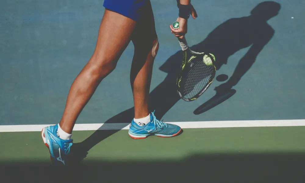Bild von Tennisplatz in gruen und blau mit Tennisspieler Tennisschuhe Tennisschlaeger beim Aufschlag