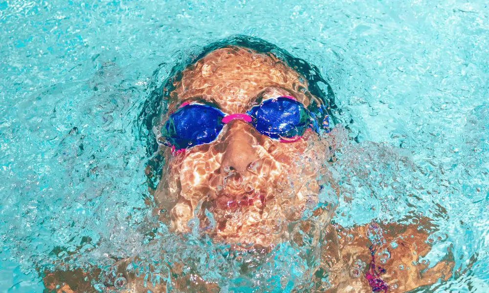 Schwimmbrille in Rot blau mit Frau unter Wasser im Swimmingpool