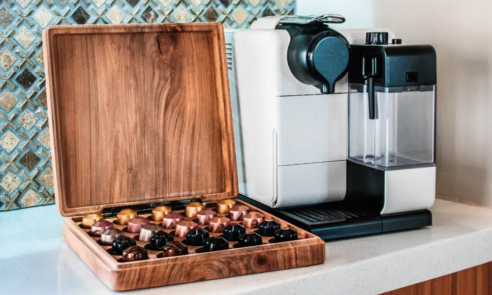 Weisse Kapselmaschine mit Kaffeekapseln in Holzgefaess