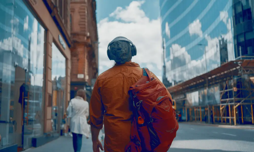 Die besten Kopfhörer für Reisen Mensch mit Rucksack und Kopfhoerern auf Strasse